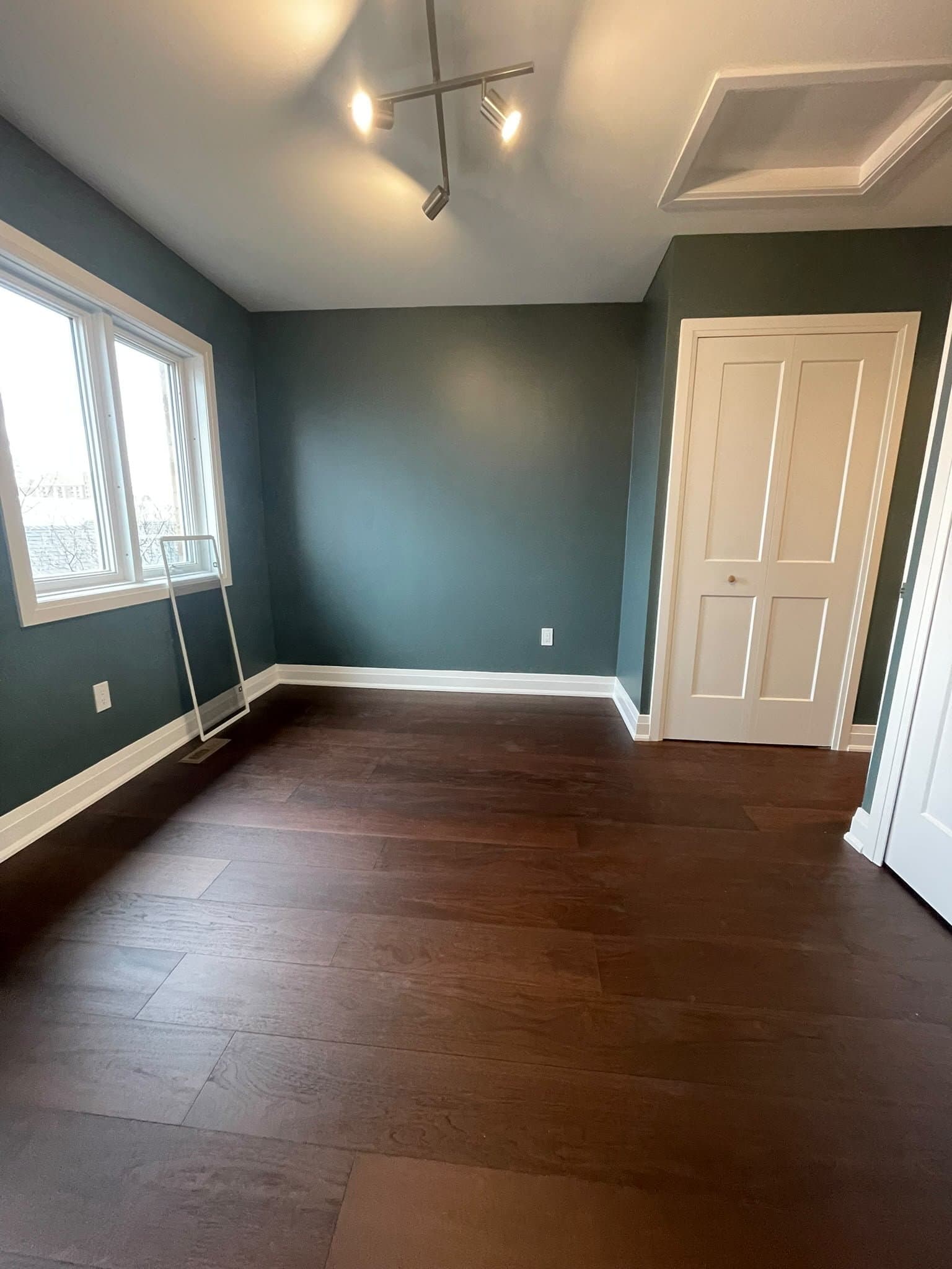 Renovated bedroom with dark wood flooring and built-in closet