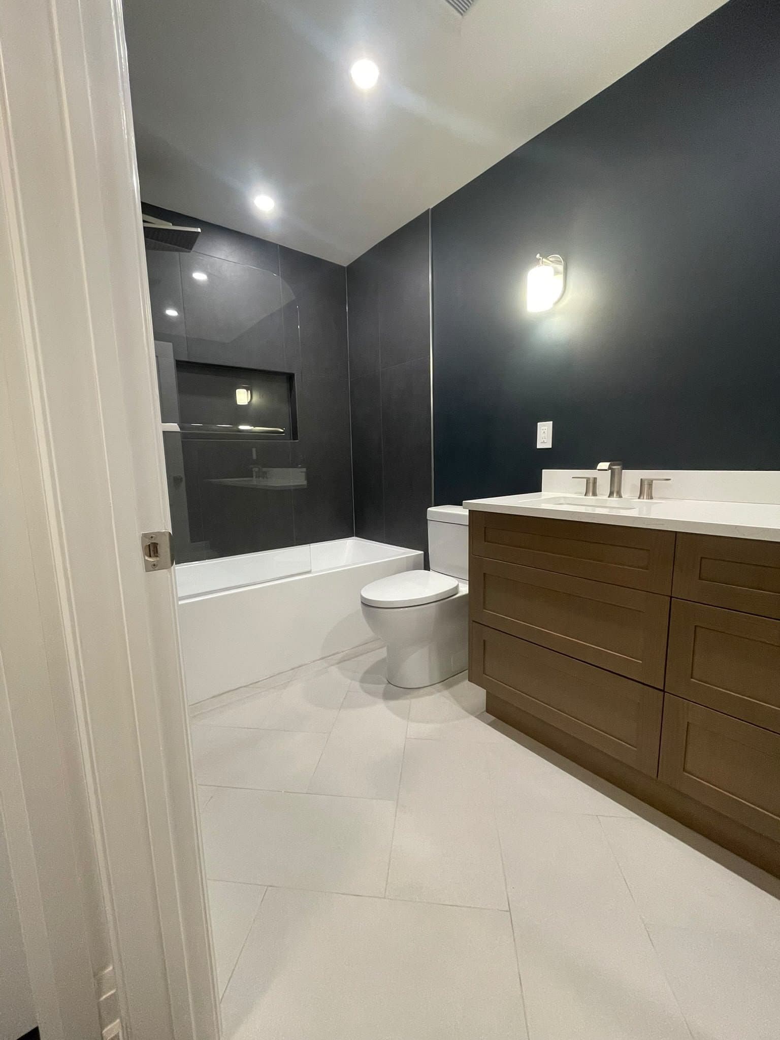 Primary bathroom with dark tile shower and wood vanity