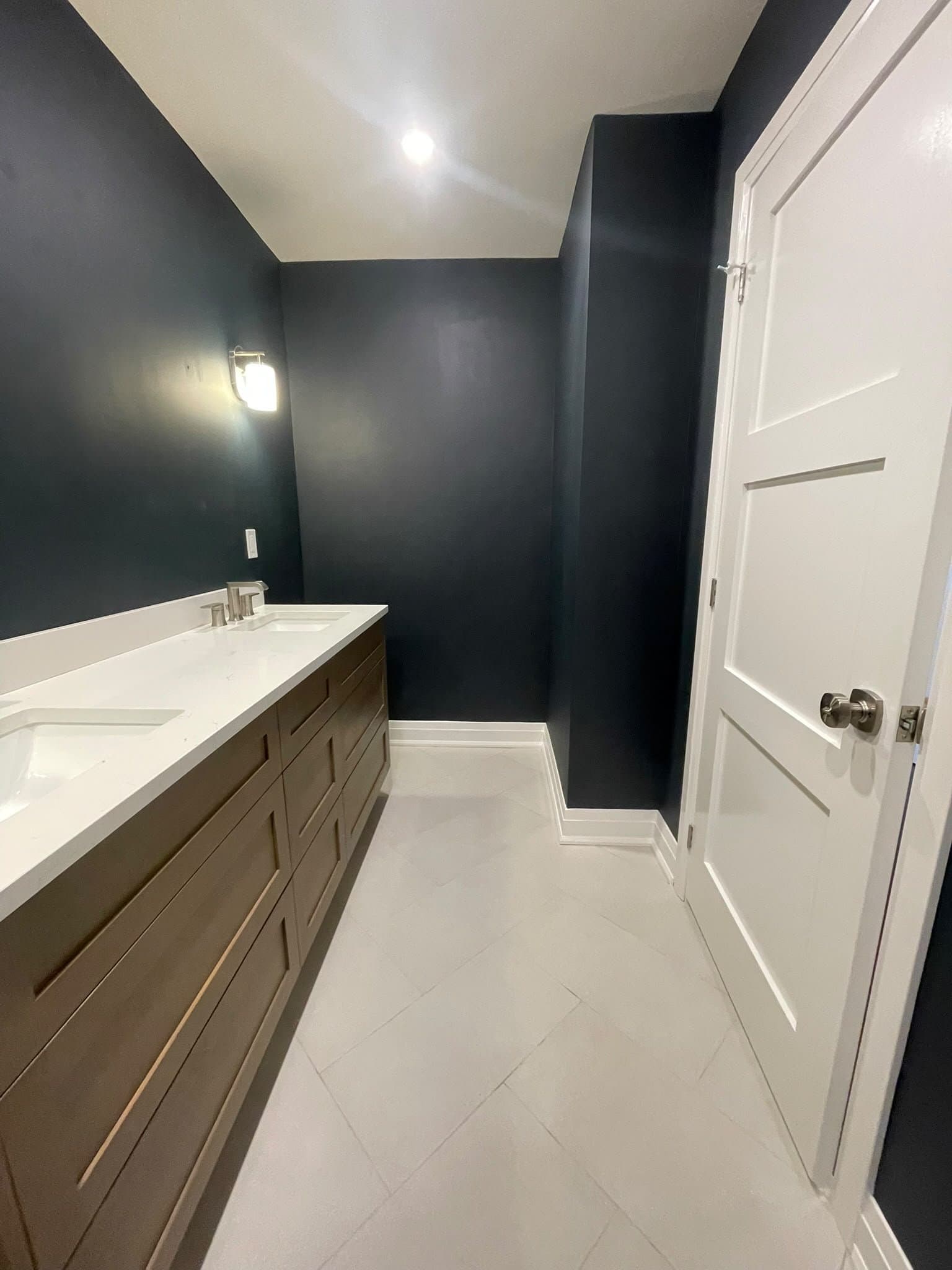 Bathroom hallway with double vanity and navy walls